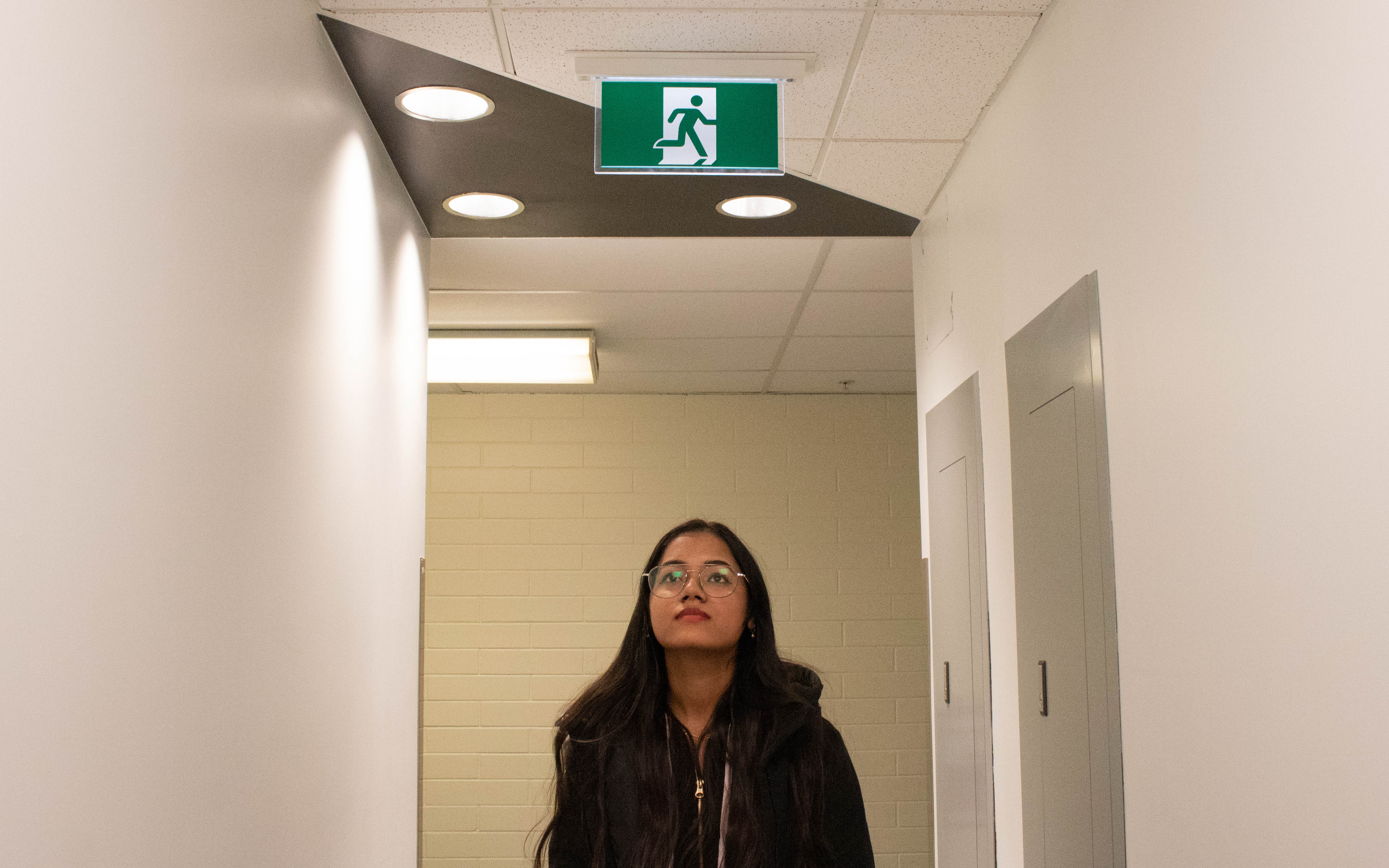 Langara student Gurvir Kaur stands below an exit sign. She plans to go straight into the workforce after her studies at Langara. Photo by Tierney Grattan