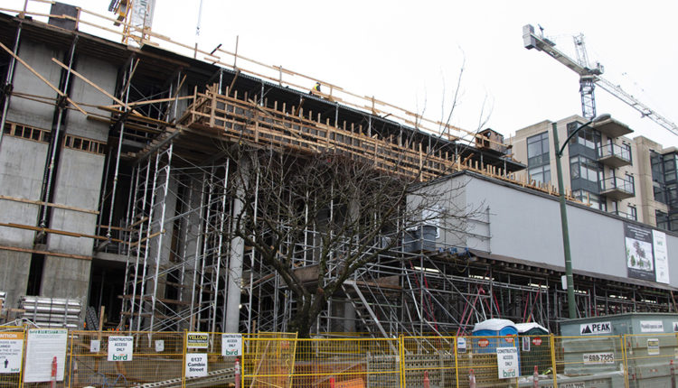 Heavy construction on Cambie Street is part of the Cambie Corridor Plan. A yellow fence divides the street from the new tower construction near the Oakridge Baptist Church.