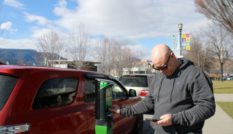 Local paying for parking on Water street in front of Kelowna City Hall.