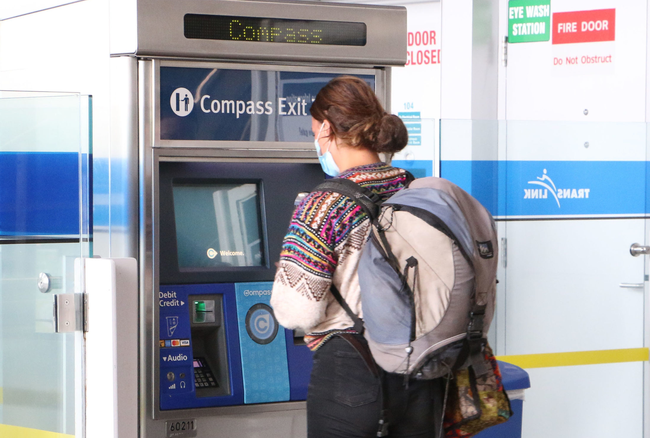 A woman stands in front of a Compass card vending machine.