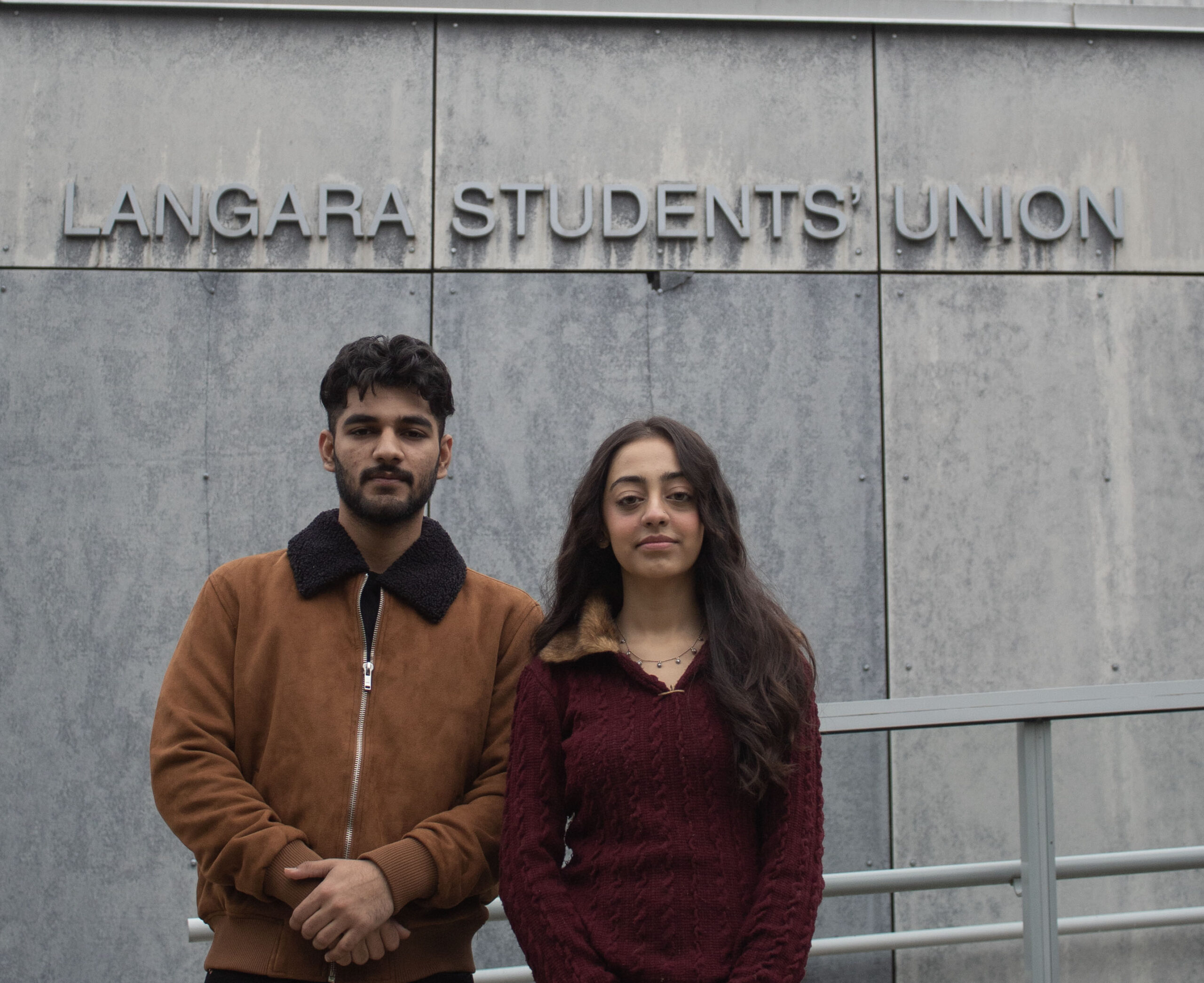 Two students standing in front of the Langara Student Union building.