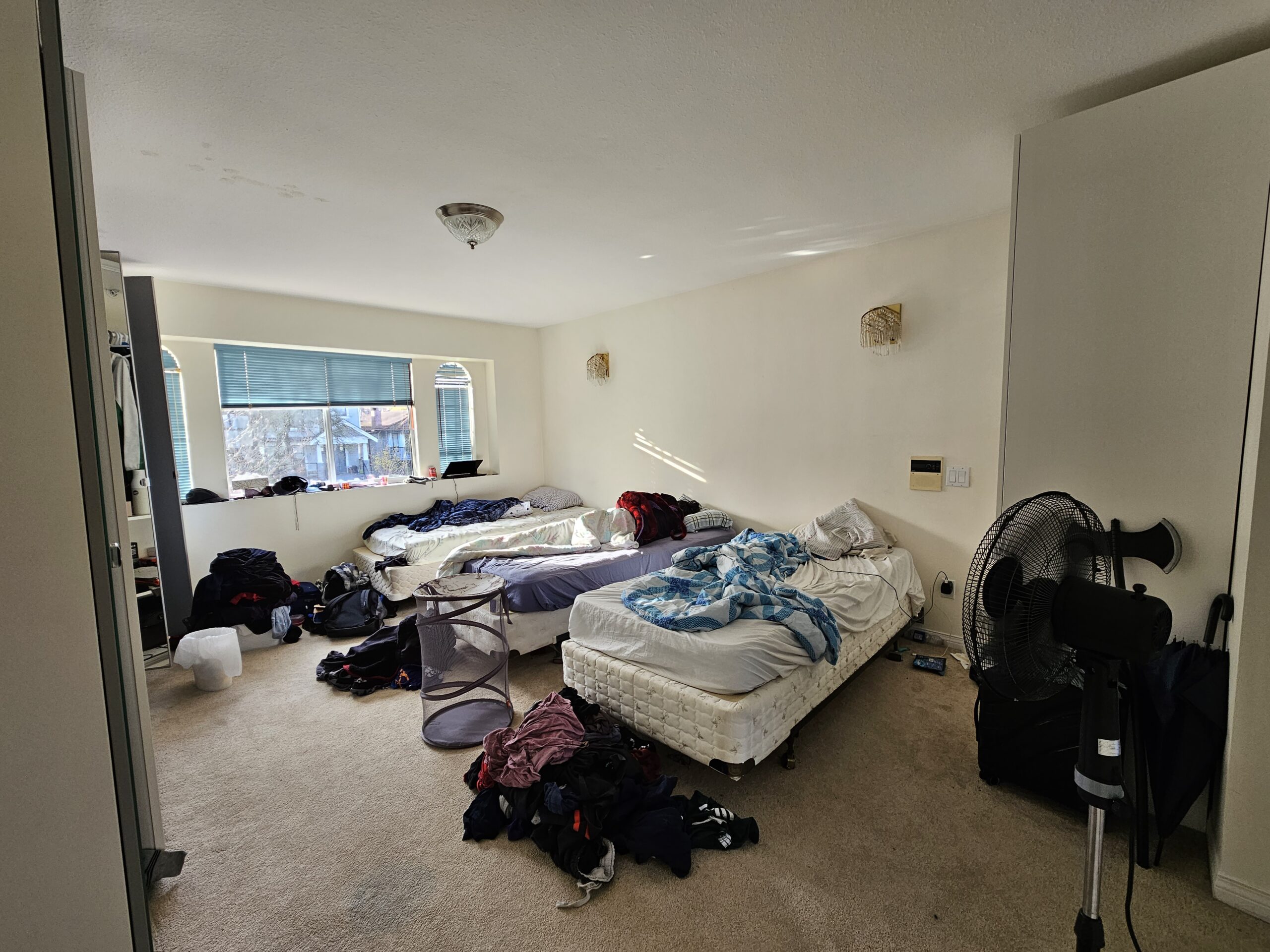 Leo Malamug's rented room that he shares with two other students. The room has three beds with clothes and various belongings on them.