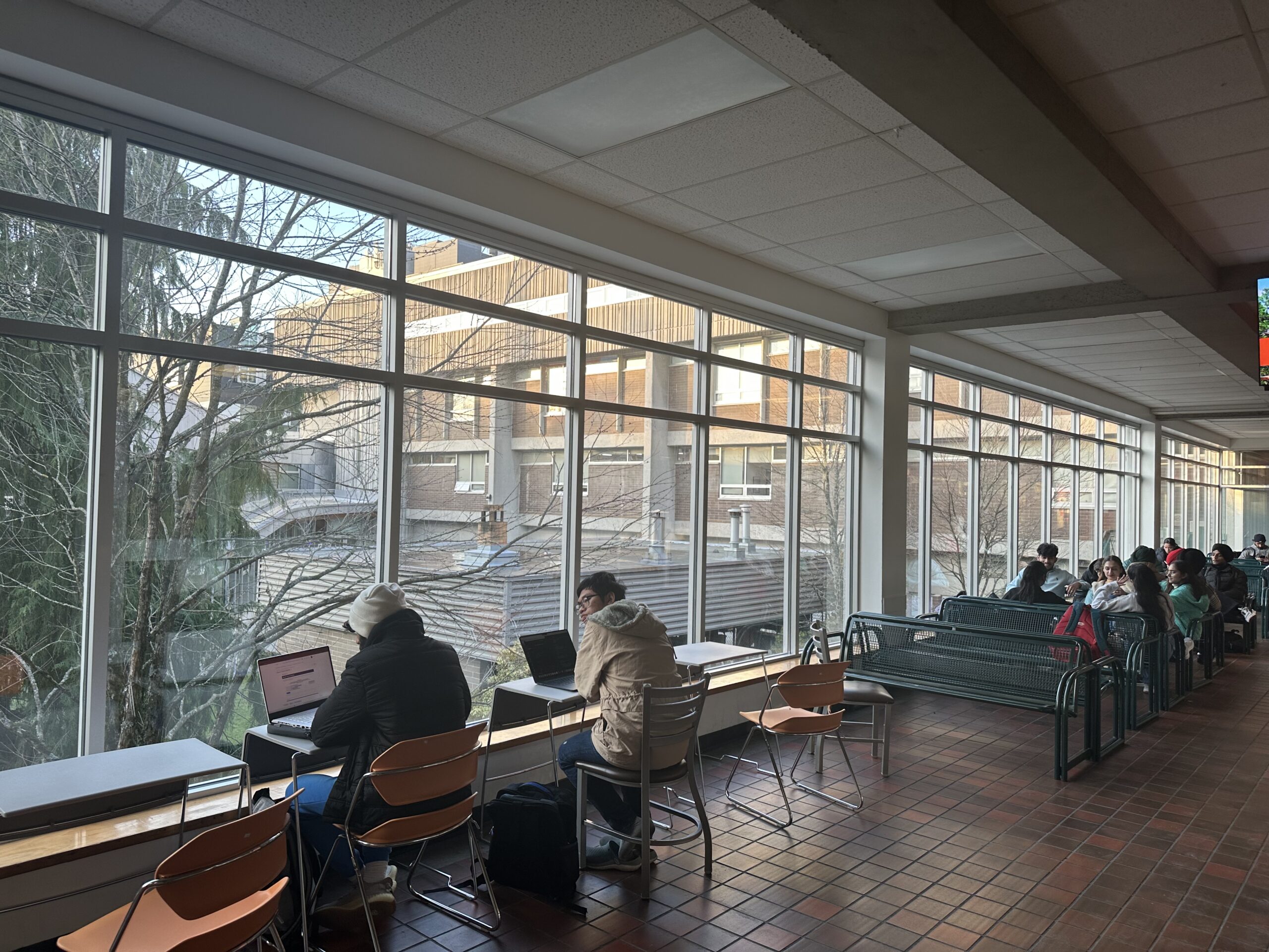 Langara students sit by windows in the seating area outside of the A Building cafeteria.