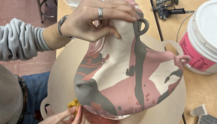 Clay Project being cleaned up with sponge on a spinning wheel.