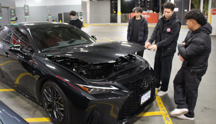 Three men standing in front of an open car hood.