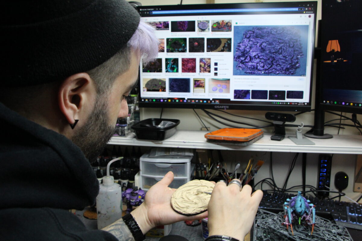 Jim Vesal places texture on a base as he uses his computer for reference
