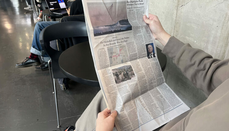 A newspaper is being held by a person sitting down.