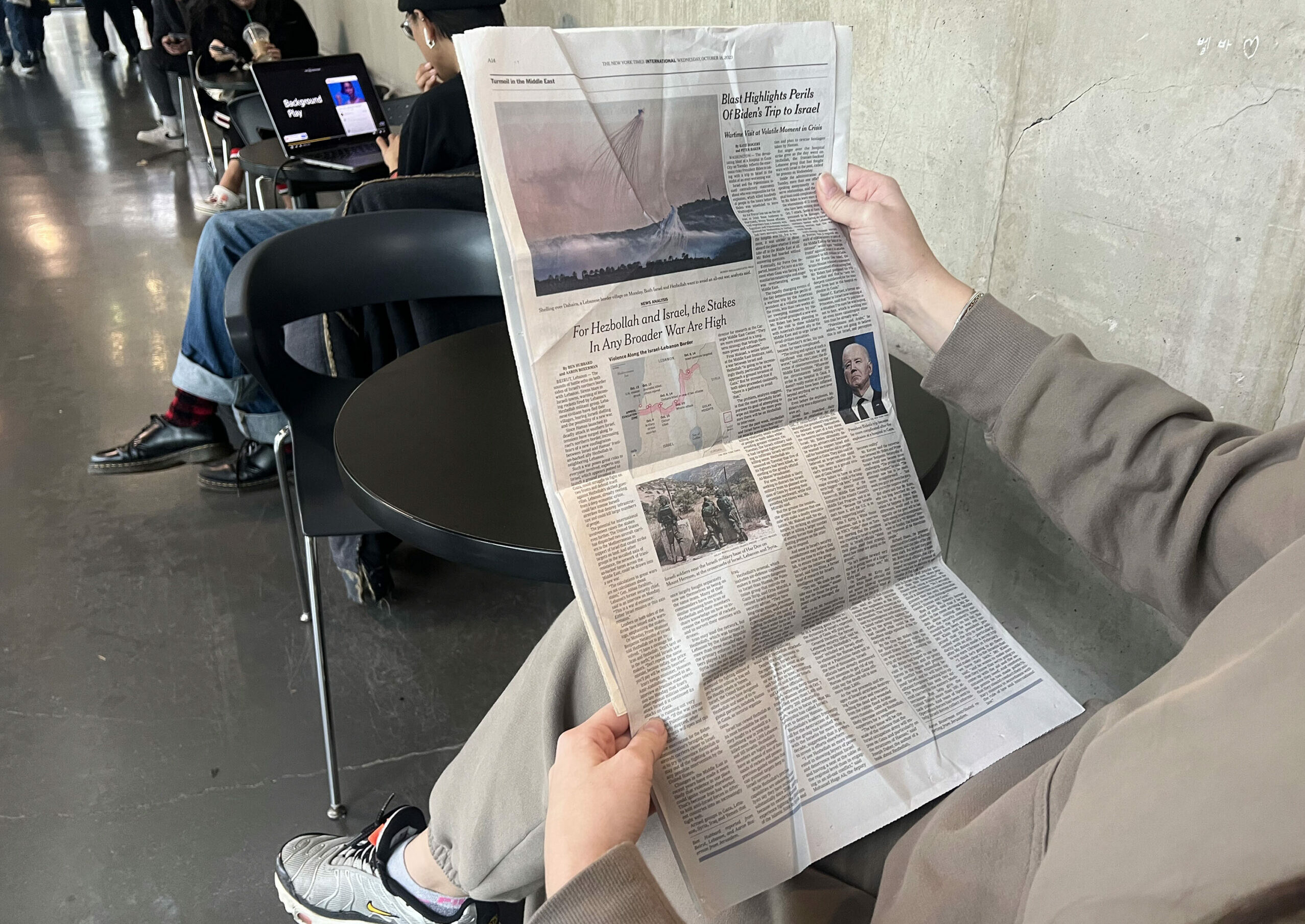 A newspaper is being held by a person sitting down.