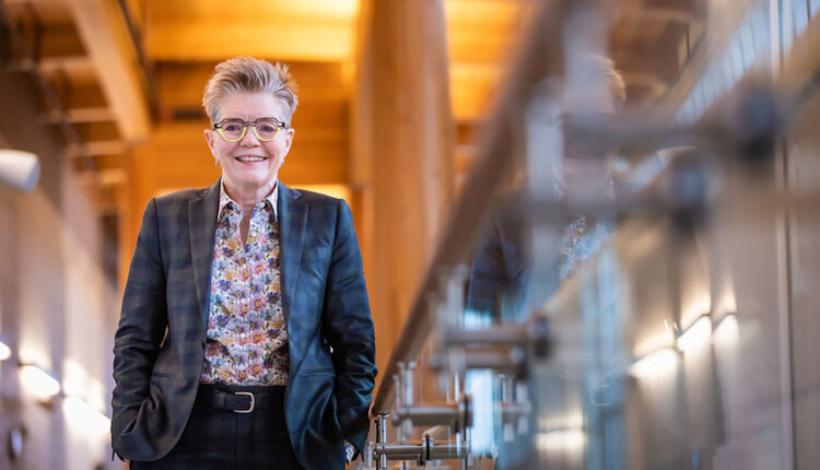 A woman wearing a suit stands along a well-lit railing.