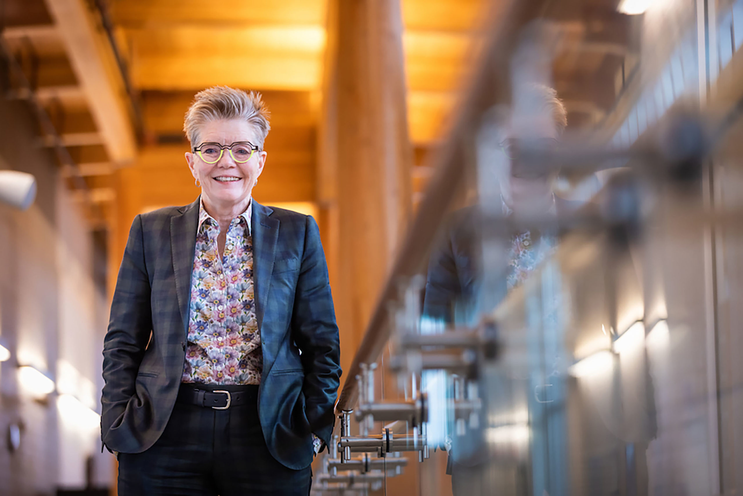 A woman wearing a suit stands along a well-lit railing.